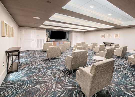 A conference room with a carpeted floor and a projector screen.