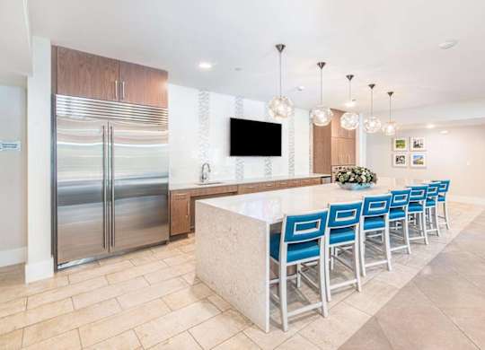 A kitchen with a bar and blue chairs.