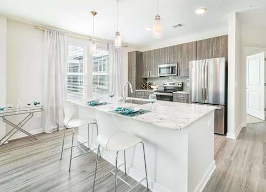 A kitchen with a white island and a breakfast bar.