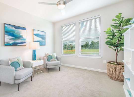 A living room with two grey couches, a ceiling fan, and two paintings on the wall.