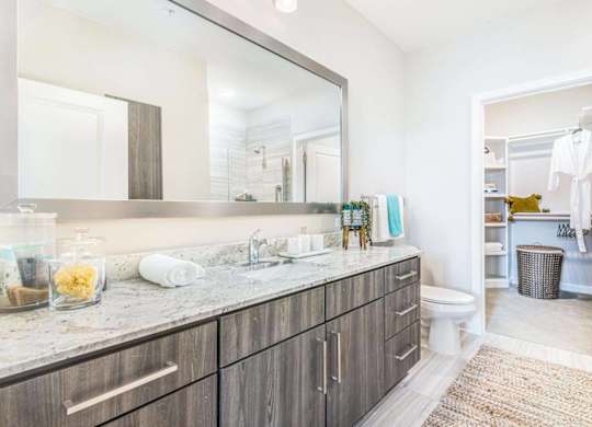 A bathroom with a marble countertop and a large mirror.