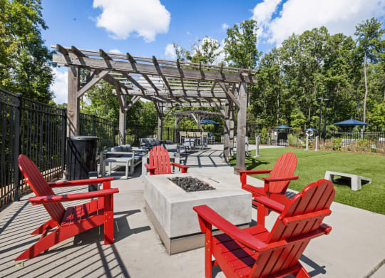 an outdoor patio with red chairs and a firepit