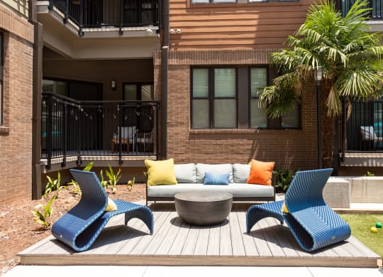 a patio with blue chairs and a couch and a fire pit