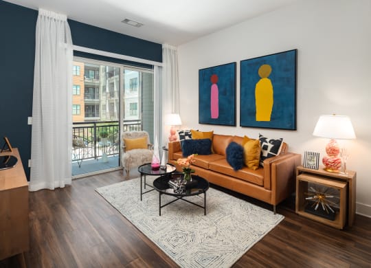 a living room with a brown couch and two paintings on the wall