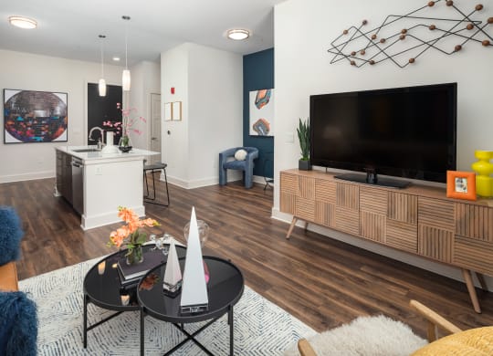 a living room and kitchen with a large tv and a table