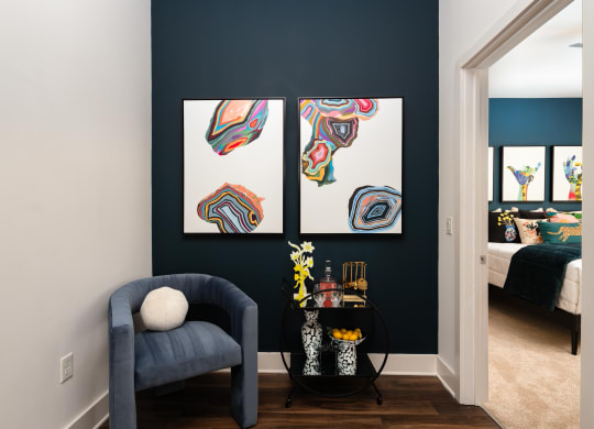 a living room with a blue chair and paintings on the wall