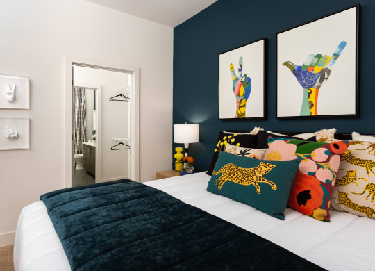 a bedroom with a bed with colorful pillows and pictures on the wall