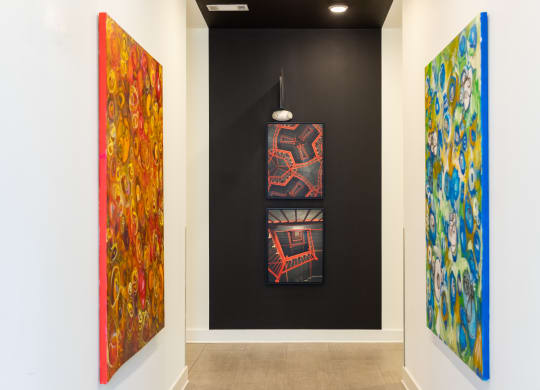 three paintings in a room with a black wall and a light fixture