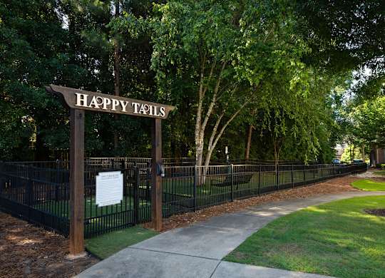 A sign that says Happy Tails is on a fence.