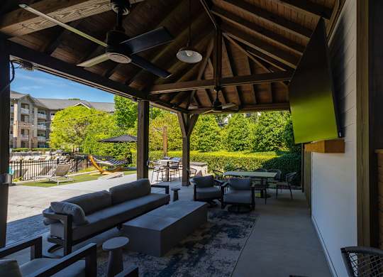 A patio with a couch and chairs under a roof.