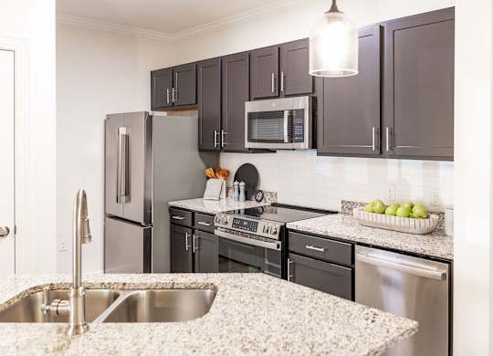A kitchen with a sink, refrigerator, oven, and microwave.