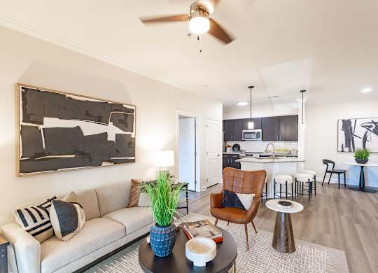 A living room with a couch, a chair, a table, and a painting on the wall.