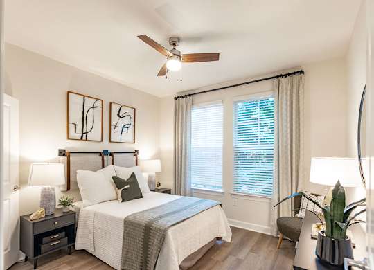 A bedroom with a bed, nightstand, and a ceiling fan.