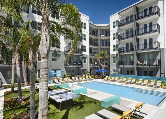 Courtyard Pool Surrounded by Lounge Chairs, Ping Pong Tables, and Palm Trees