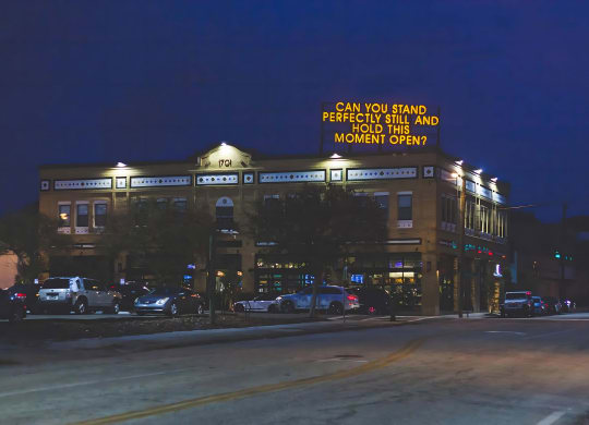 Evening View of Brick Building with Artistic Rooftop Message and Street Lighting