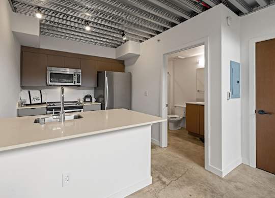 A kitchen with white countertops and a brown cabinet.