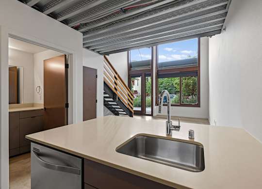 A kitchen with a stainless steel sink and a window overlooking a staircase.