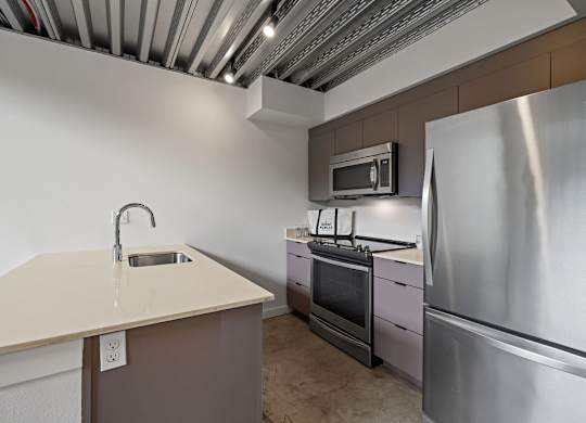 A kitchen with a stainless steel refrigerator, microwave, and oven.