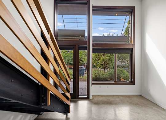 A room with a wooden staircase and a glass door leading to a balcony.