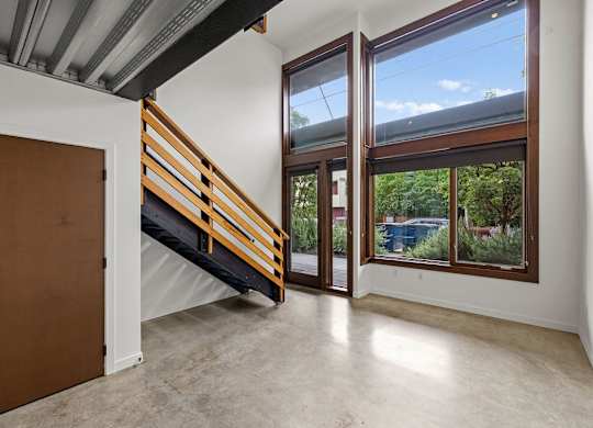 A room with a brown door and a staircase leading to a balcony.