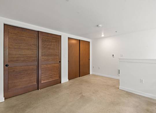 A room with two brown doors and a white wall.