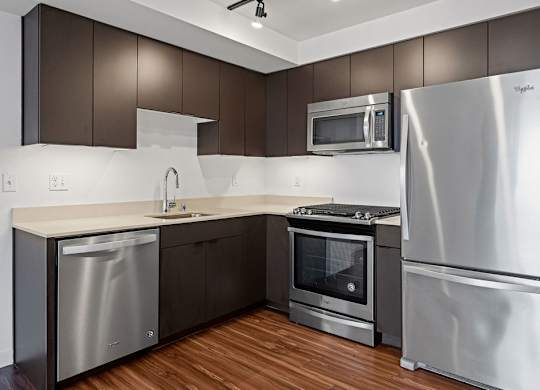 A modern kitchen with stainless steel appliances and wooden floors.
