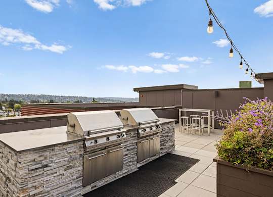 A stone outdoor kitchen with a grill and a table.