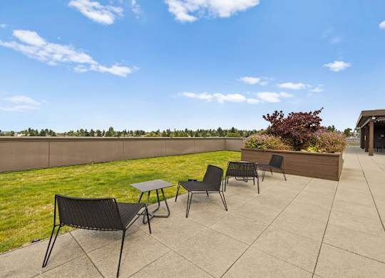 A patio with a table and chairs overlooking a grassy field.
