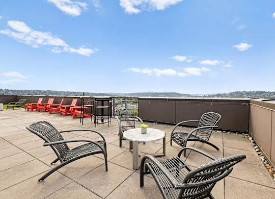 A patio with black metal chairs and tables overlooks a cityscape.