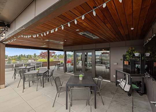 A patio with tables and chairs and a wooden ceiling.