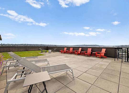 A patio with tables and chairs overlooking a grassy area.
