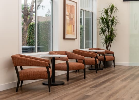 a seating area with tables and chairs in a room with large windows