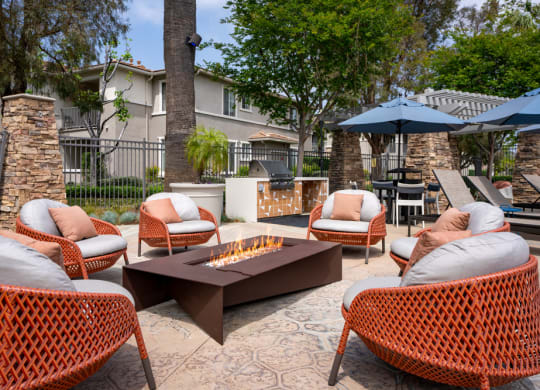 a patio with chairs and a table with a fire pit