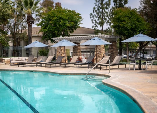a swimming pool with umbrellas and chairs near a resort pool