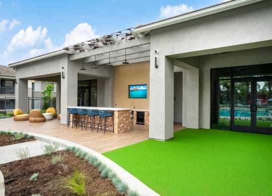 a patio with a bar and green grass in front of a house