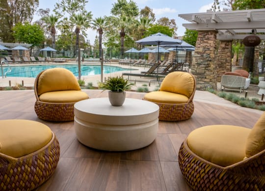 a lounge area with chairs and a table near a pool