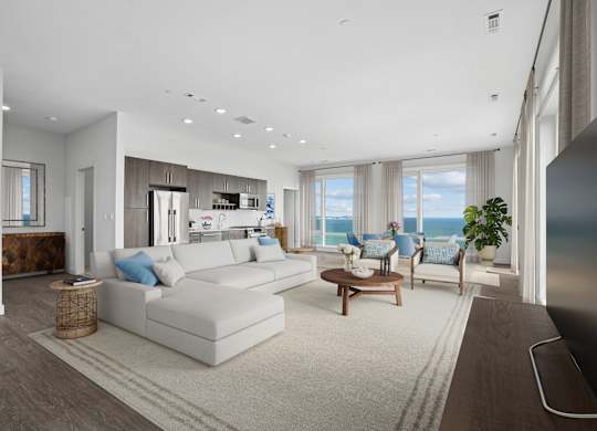 Penthouse great room with seating, a dining area and a kitchen along one wall, with windows out to open water.