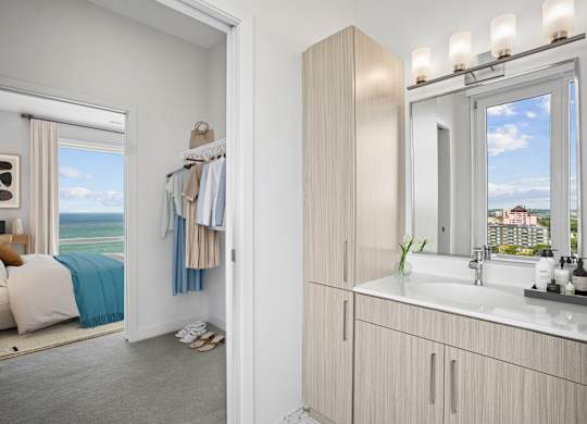 Penthouse bathroom with a quartz vanity, a tall linen tower and a window, open to a spacious closet and the bedroom.