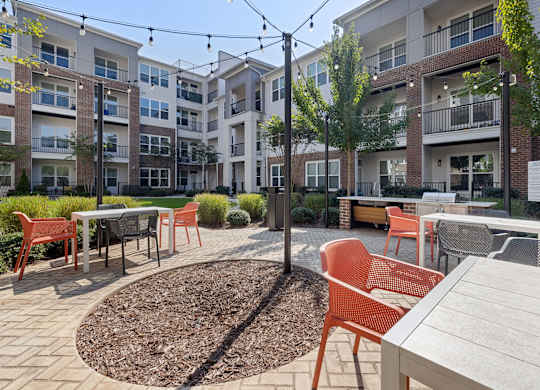 A courtyard with tables and chairs surrounded by apartment buildings.
