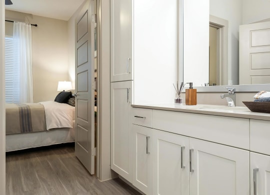 Connected Bathroom Featuring Double Vanity and Linen Cabinet