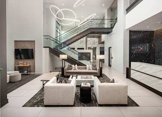 A modern living room with a staircase and a glass railing.