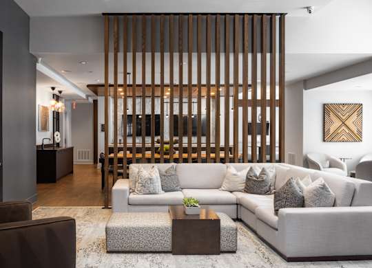 A modern living room with a large couch and a wooden slat wall.