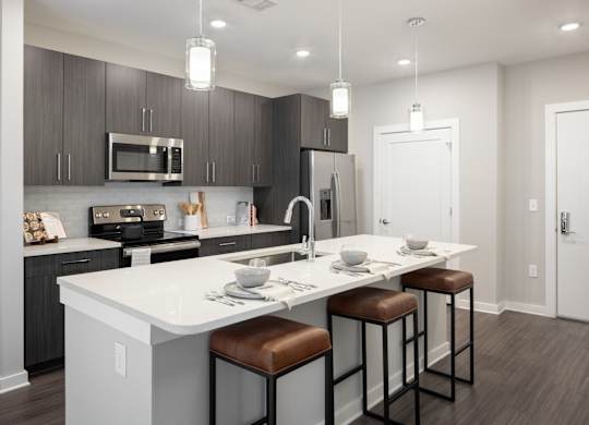 A modern kitchen with a white island and brown bar stools.