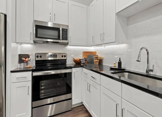 White Cabinet Kitchen with Hexagon Tile Backsplash and Black Counters