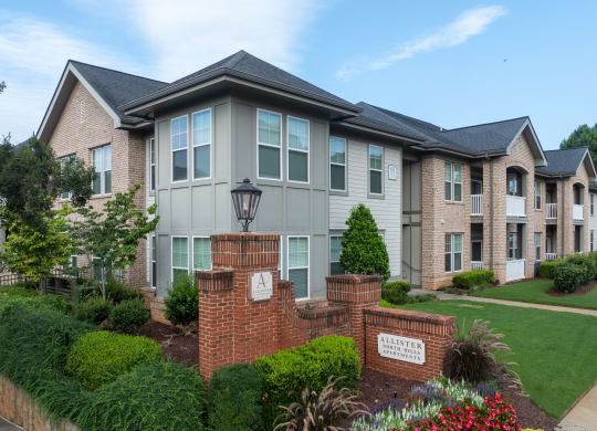 an apartment building with a lawn and a sidewalk in front of it