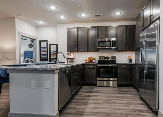 U-Shaped Kitchen with Dark Cabinetry and Granite Countertops