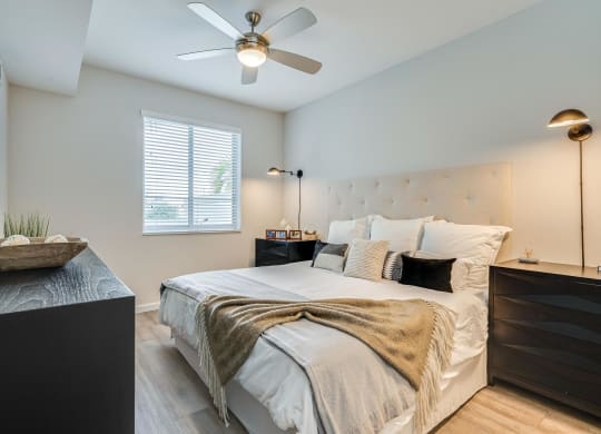 Bedroom Featuring Ceiling Fan, Tufted Headboard, and Window with Blinds