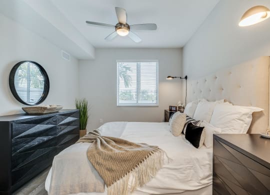 Bedroom Includes Black Dresser, Round Mirror, and Ceiling Fan