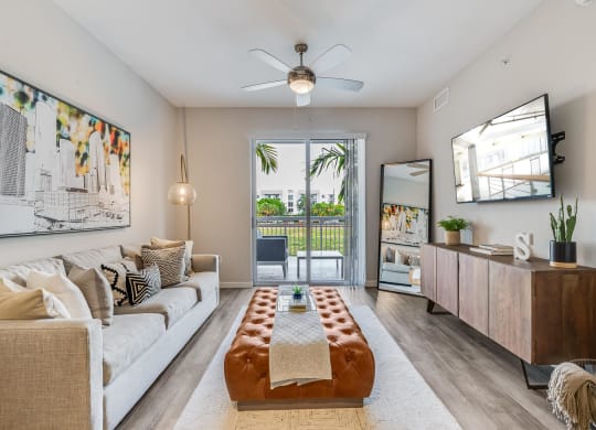 Living Room with Wall-Mounted TV, Balcony View, and Ceiling Fan