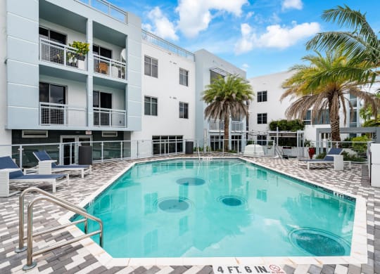 Pool Area Surrounded by Palm Trees and Chaise Seating